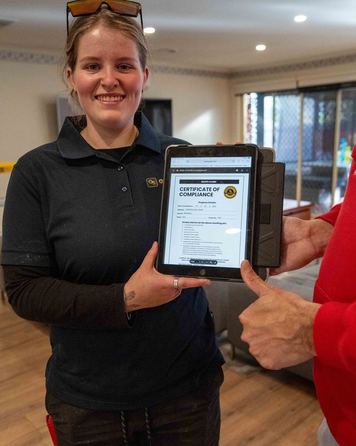 Goldsure team member with a Certificate of Compliance for a completed install